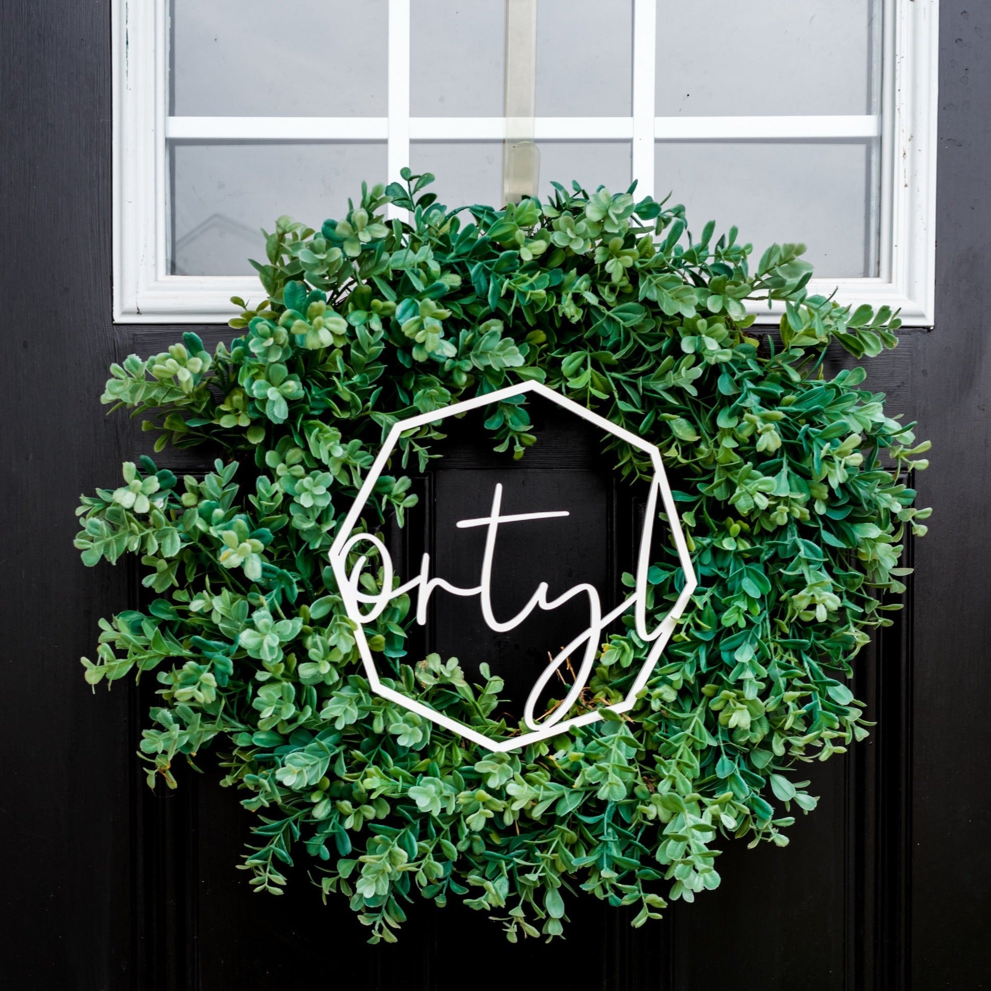 Last Name Wreath Sign - in green wreath on black door by LeeMo Designs in Bend, Oregon